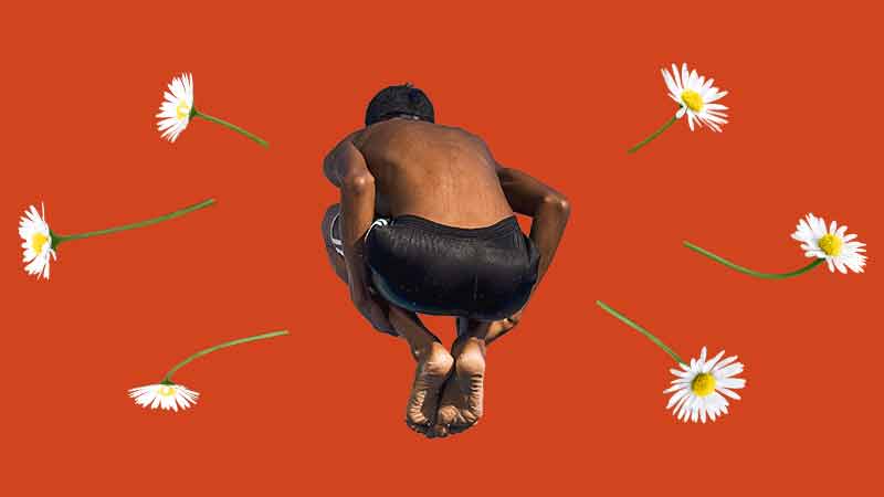 person jumping with feet tucked in surrounded by daisies