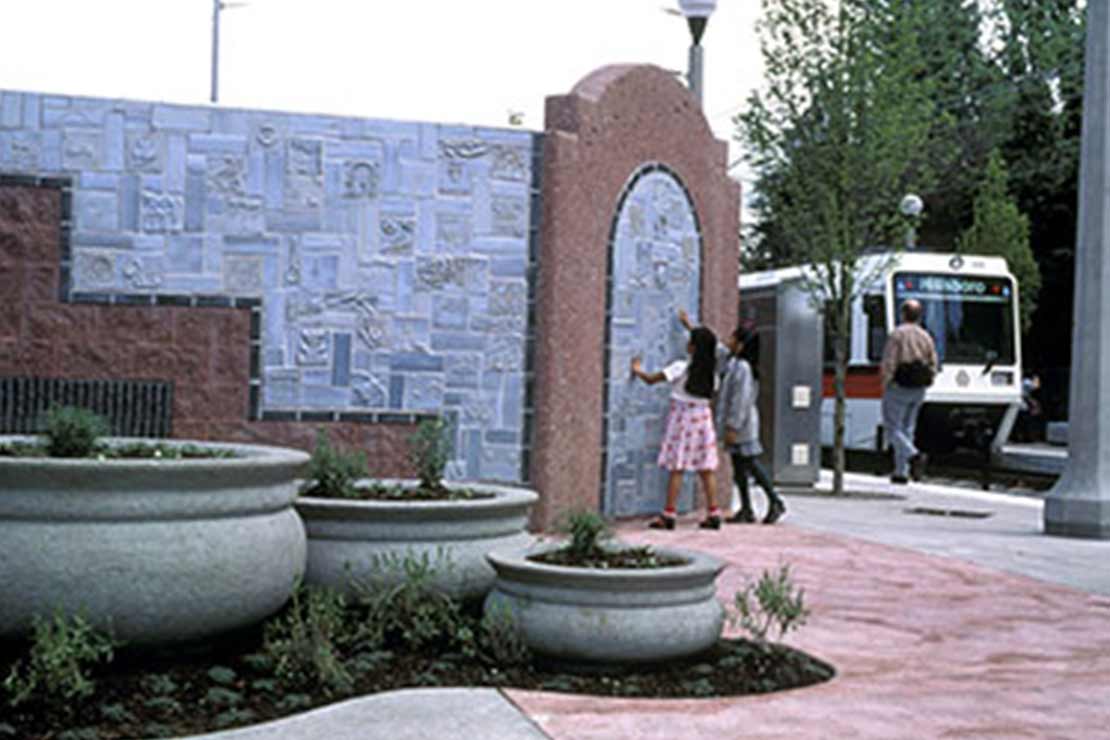 Tile wall and planters with MAX light rail train in the background