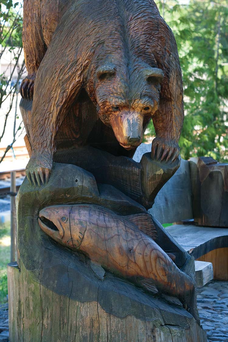 A carved wooden sculpture of a bear catching salmon