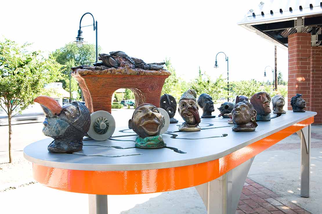 The Tualatin Interactivator sculptural heads with masks on a metal platform