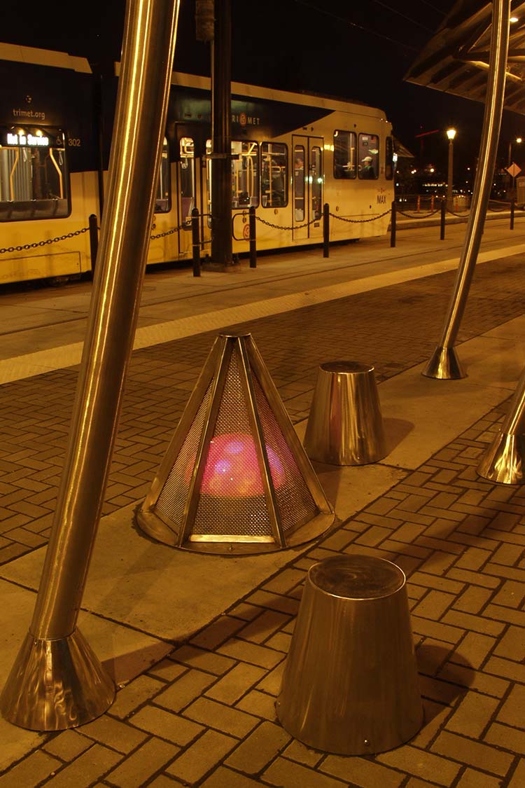 Virtual campfire and stumps low metalic sculpture with red ball in a cage